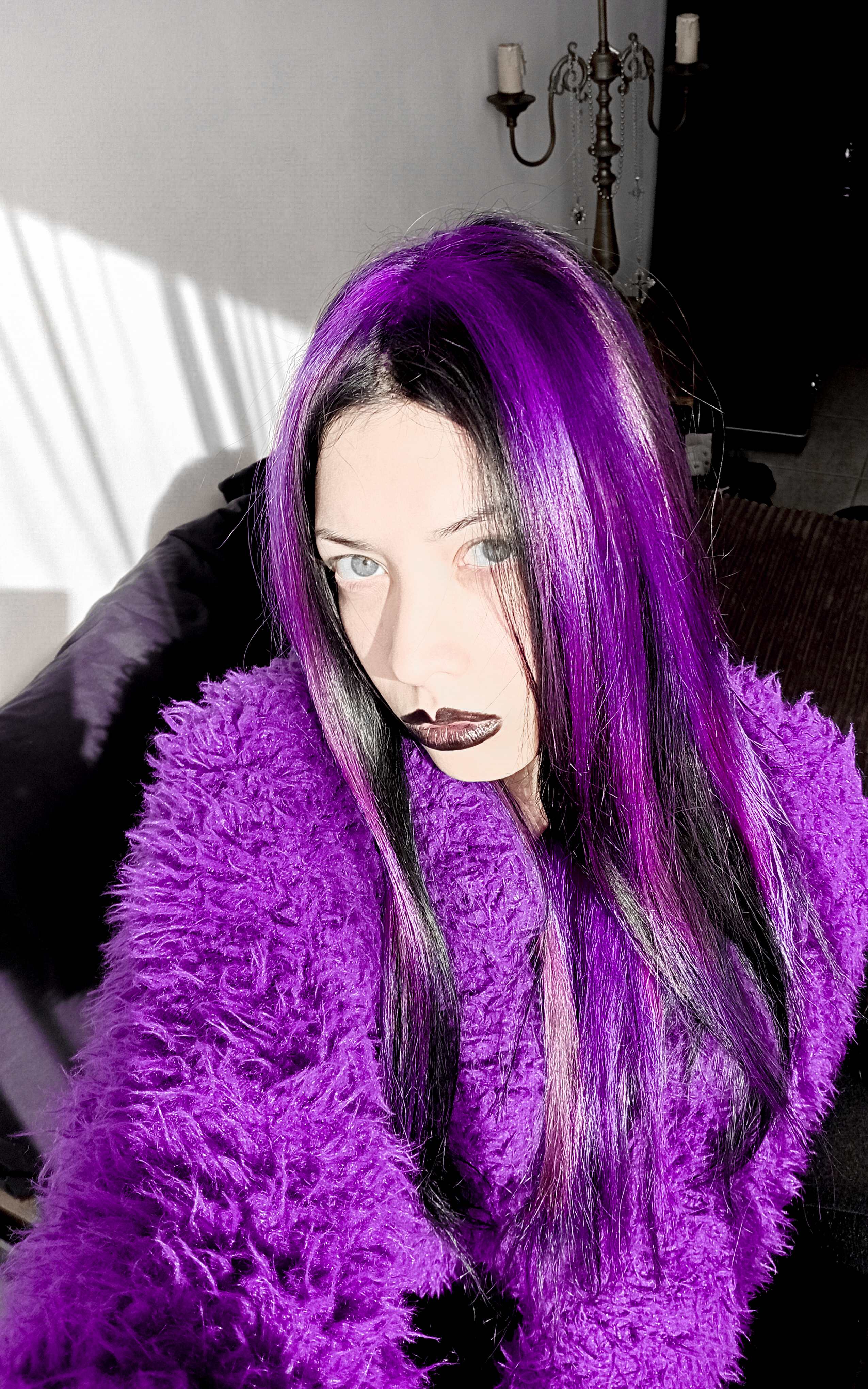 Zoe in a purple fluffy coat with vivid purple-streaked black hair and dark lips